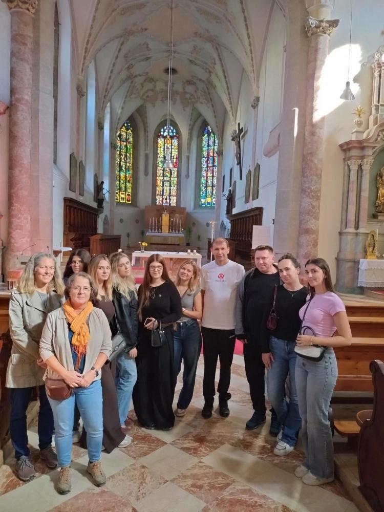 Gruppe von Personen in einer Kirche mit bunten Glasfenstern und einem Altar